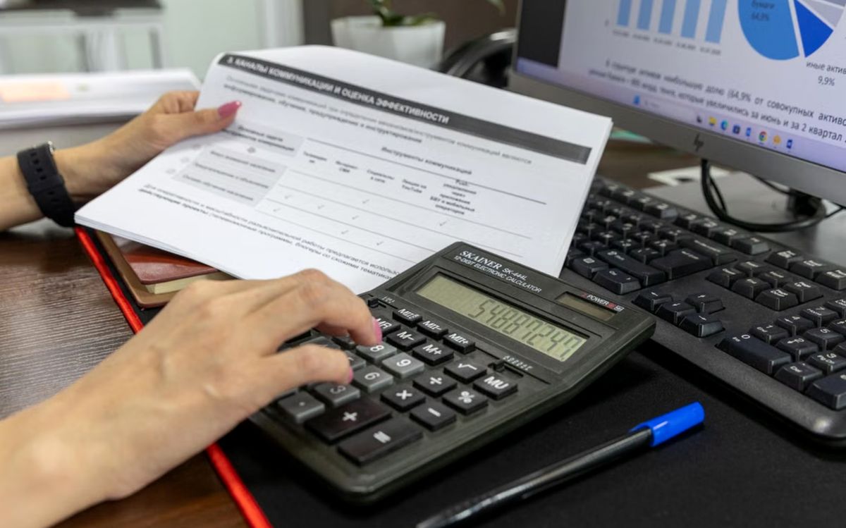Accountant entering figures on a calculator beside a ledger report