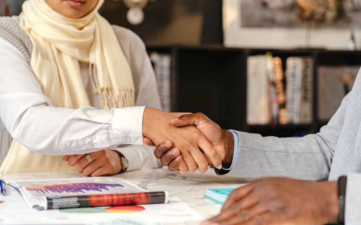 Business partners shaking hands across a desk after agreeing a company setup