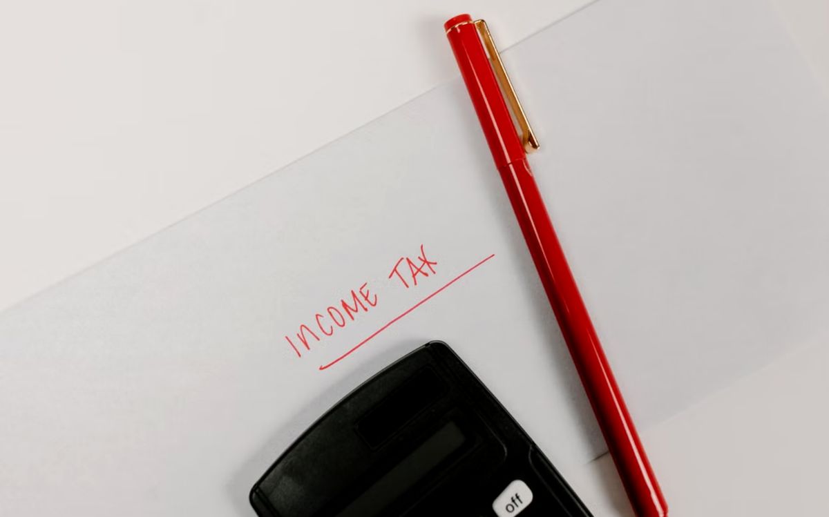 Income tax paperwork with a calculator and red pen